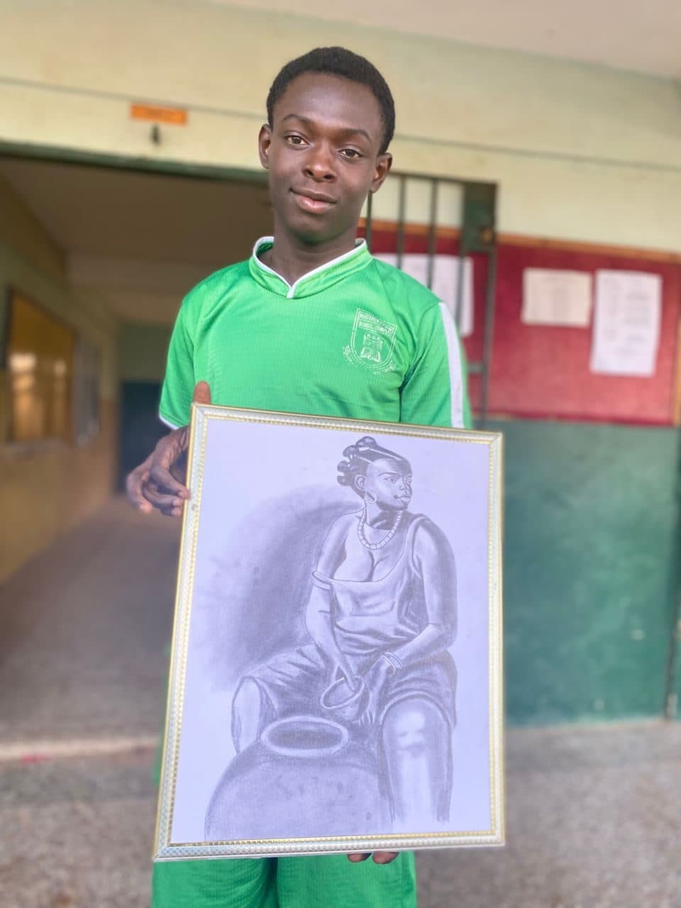 Student holding a detailed graphite portrait sketch